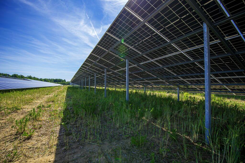 Module eines Solarparks in Franken von unten bei blauem Himmel und Sonnenschein