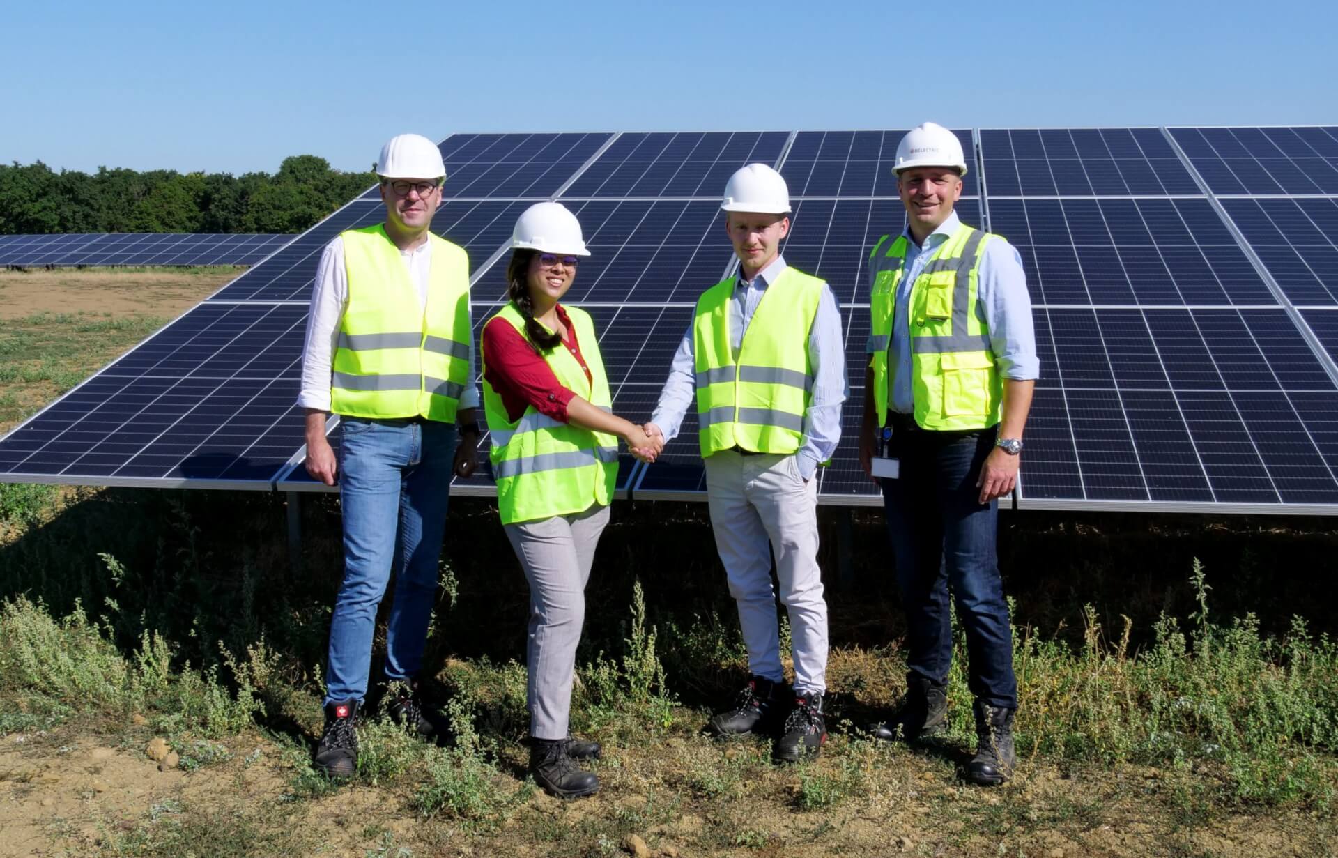 Vier Vertreter*innen der Unternehmen ÖKORENTA und BELECTRIC schütteln vor einem Solarpark die Hände