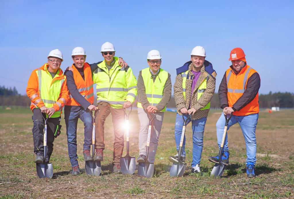 BELECTRIC employees who work in solar energy stand on the construction site, of the solar farm Borrentin, hodling spades in their hands