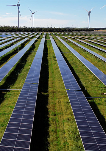 A solar tracker system in Denmark with wind turbines in the back