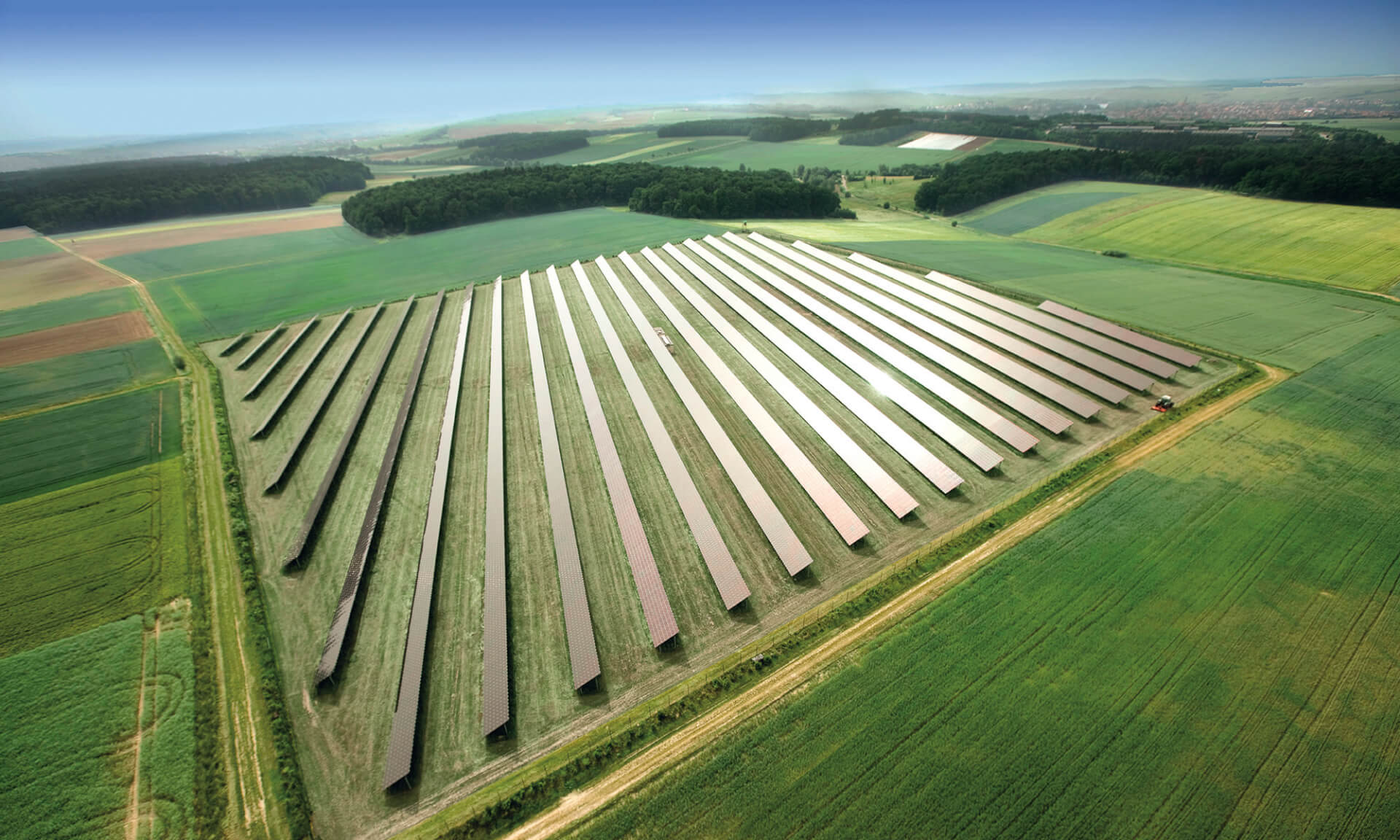 solar power plant with many green fields next to it seen from above