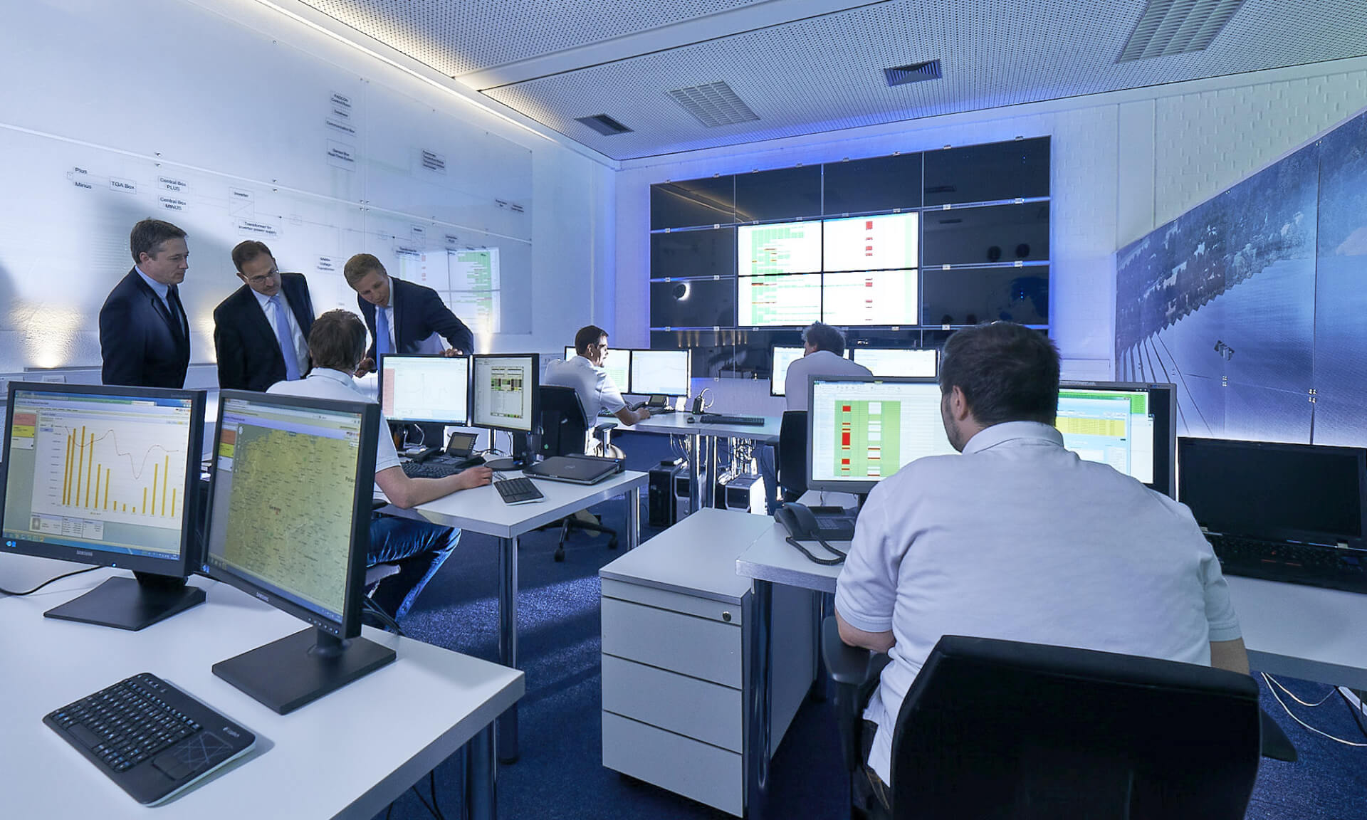 employees working in an office with many screens in front of them