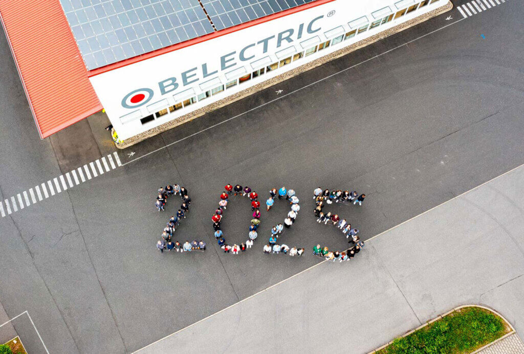 A large number of employees are photographed from above, forming the number 2025.