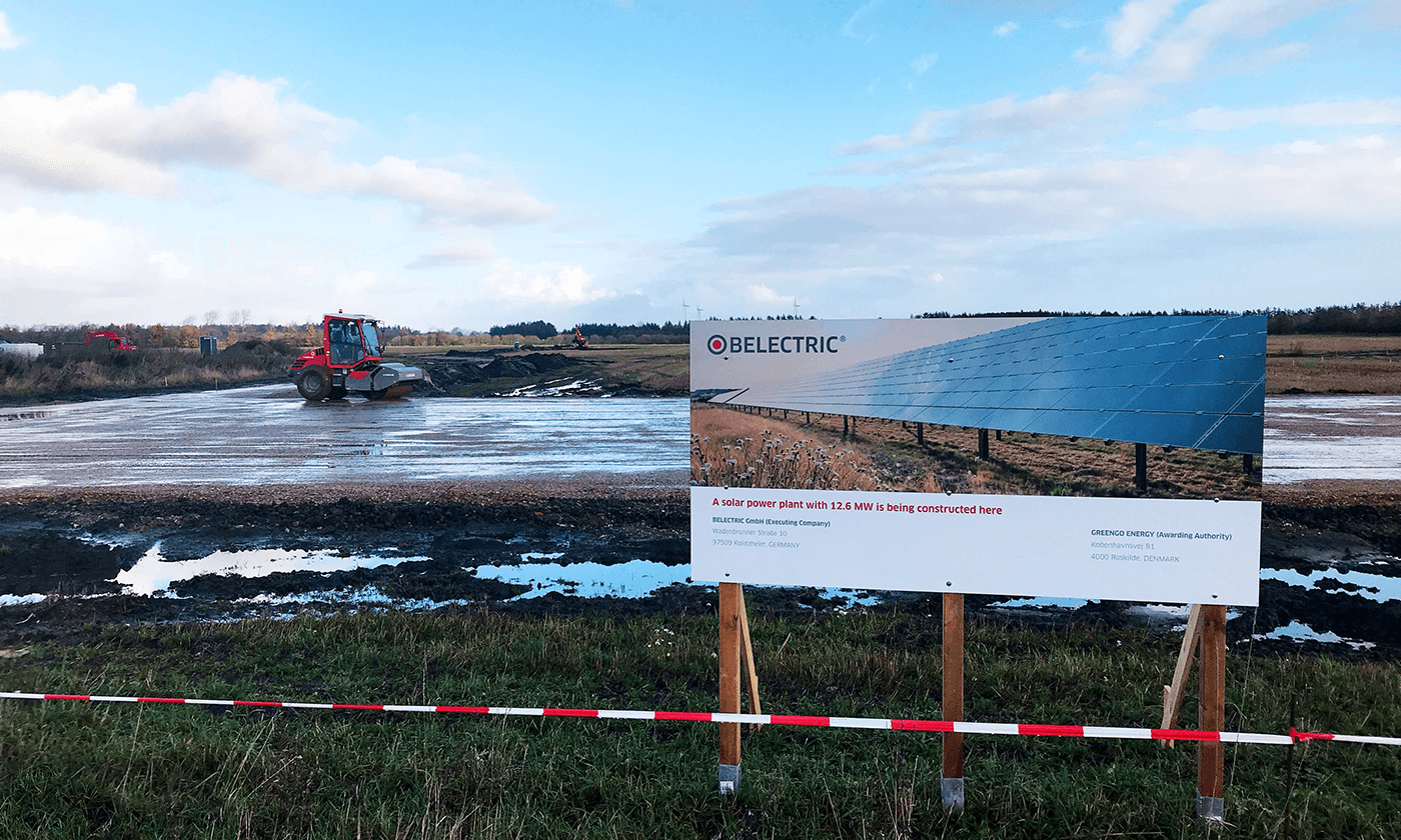 construction site of a solar farm with a construction machine in the background