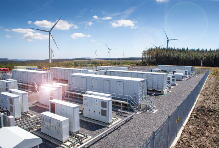 Battery Storage System constructed by BELECTRIC UK with wind turbines in the background