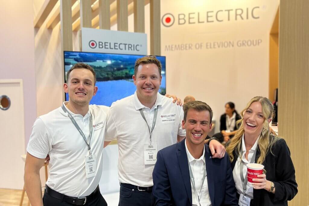 Four employees of BELECTRIC, a solar energy company, in front of the exhibition stand at Solar & Storage Live.