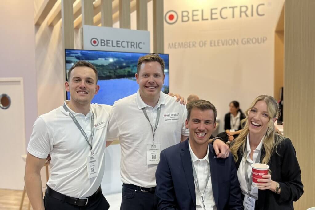 Four employees of BELECTRIC, a solar energy company, in front of the exhibition stand at Solar & Storage Live.