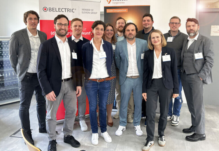 Bei BELECTRIC fand ein Cluster-Treff zum Thema Batteriespeicher statt. Auf dem Bild stehen einige der Teilnehmerinnen und Teilnehmer für ein Gruppenfoto zusammen und lächeln in die Kamera.