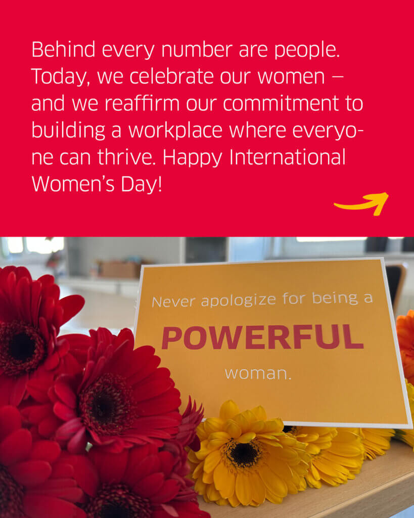 A photo showing flowers and a postcard with the text "Behind every number are people. Today, we celebrate our women - and we reaffirm our commitment to building a workplace where everyone can thrive. Happy International Women's Day!".