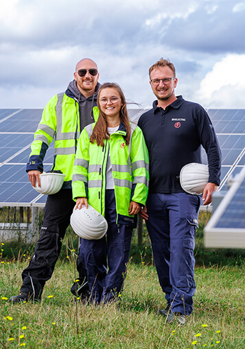 Drei BELECTRIC-Mitarbeitende, die an 360-Grad BESS-Lösungen mitarbeiten, stehen auf einem Solarpark.