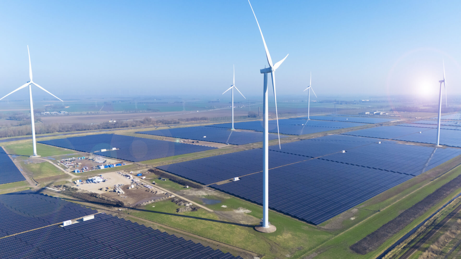 Der Solarpark Eekerpolder in den Niederlanden aus der Vogelperspektive. Zu sehen ist ein großer Solarpark mit Windturbinen.