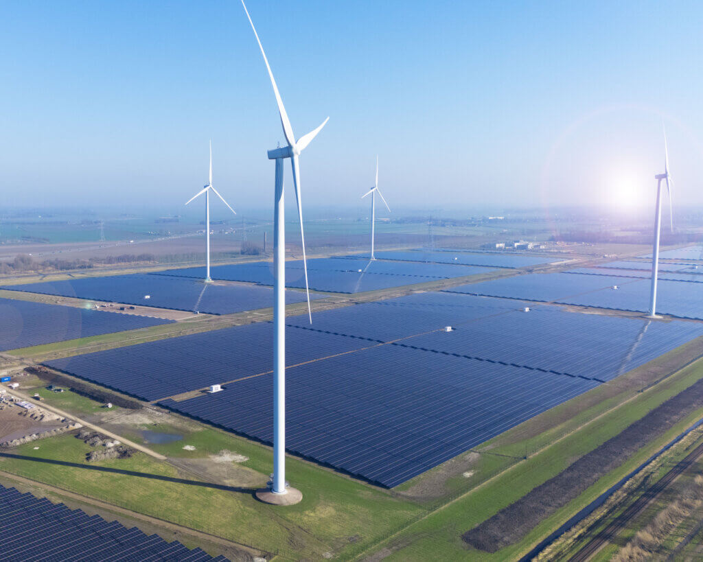 A Dutch solar farm constructed by BELECTRIC is shown from above alongside wind turbines