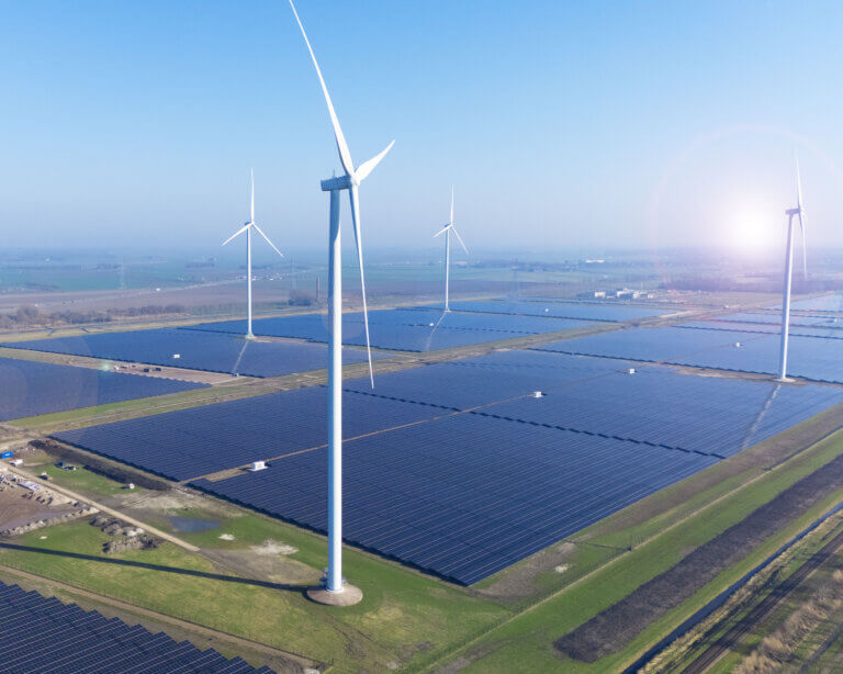 A Dutch solar farm constructed by BELECTRIC is shown from above alongside wind turbines
