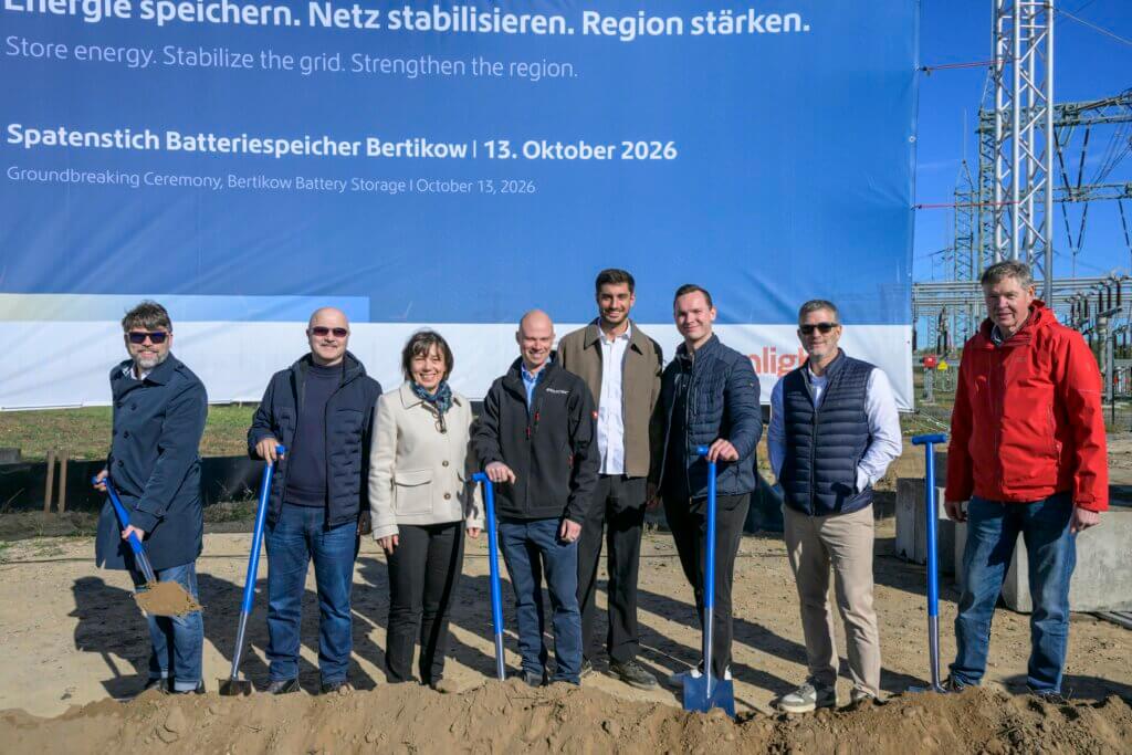 The photo shows eight people with shovels standing in front of a big sign about the BESS project Bertikow