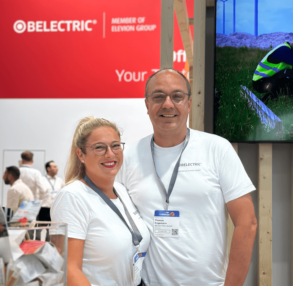 Two employees at one of BELECTRIC's trade fair appearances smile into the camera.
